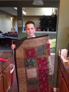 Nathan standing with finished quilt